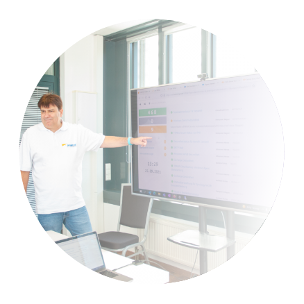 Der Inhaber des IT-Systemhaus präsentiert Ergebnisse einer IT-Analyse vor seinen Kunden auf einem digitalen Whiteboard.